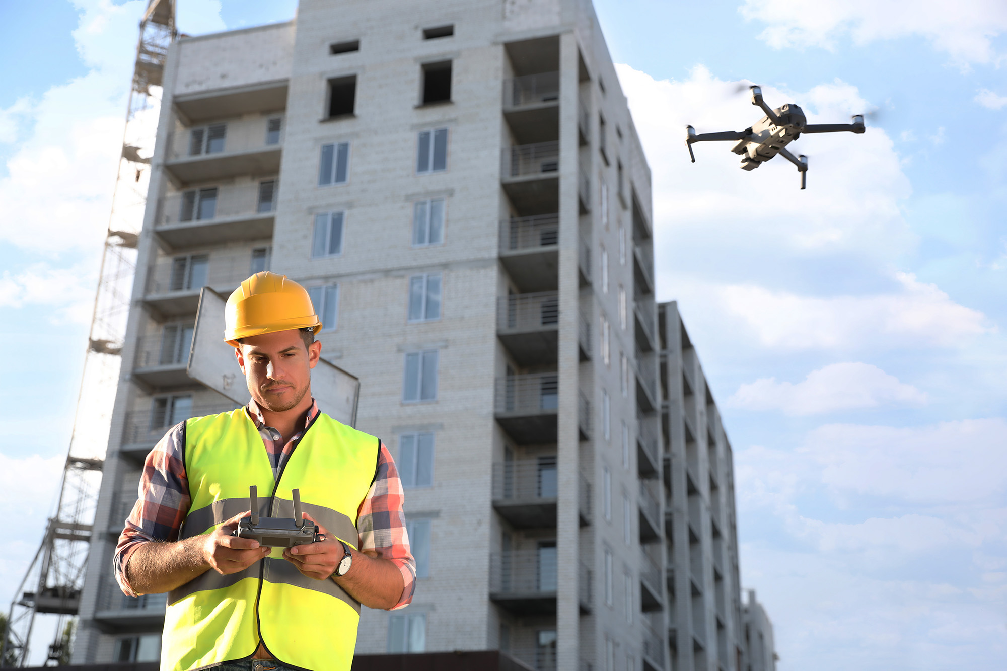 Builder operating drone with remote control at construction site. Aerial photography