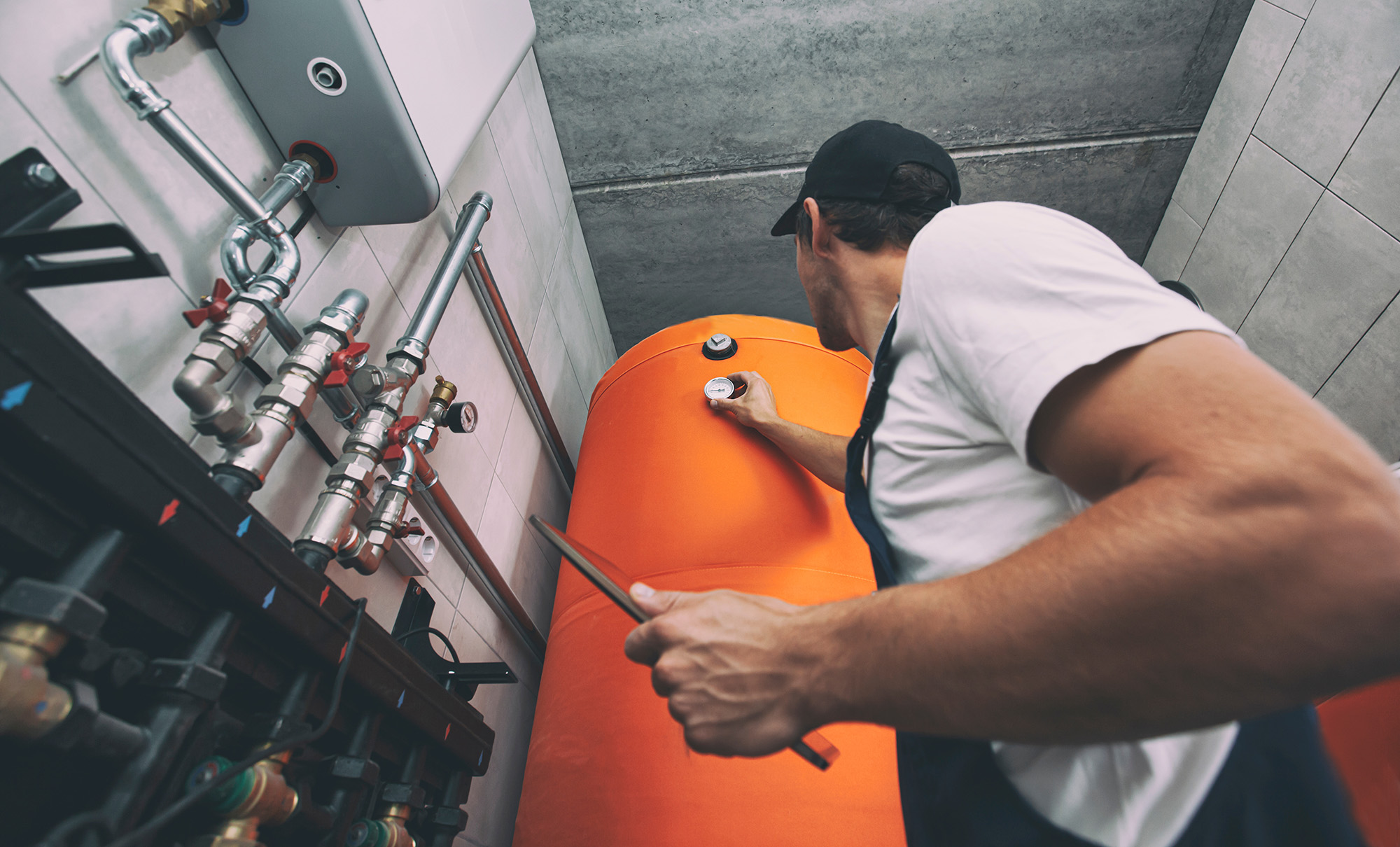 Technician checking the heating system in the boiler room with tablet in hand