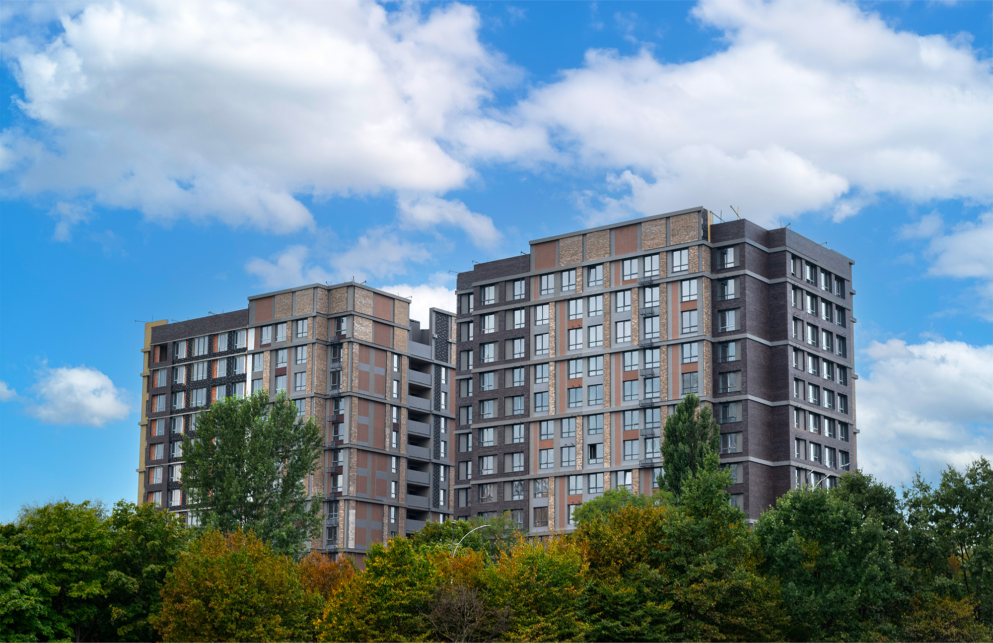 Brown modern apartment buildings over blue sky. New multifamily complex in Kyiv, buildings exterior and city life concepts