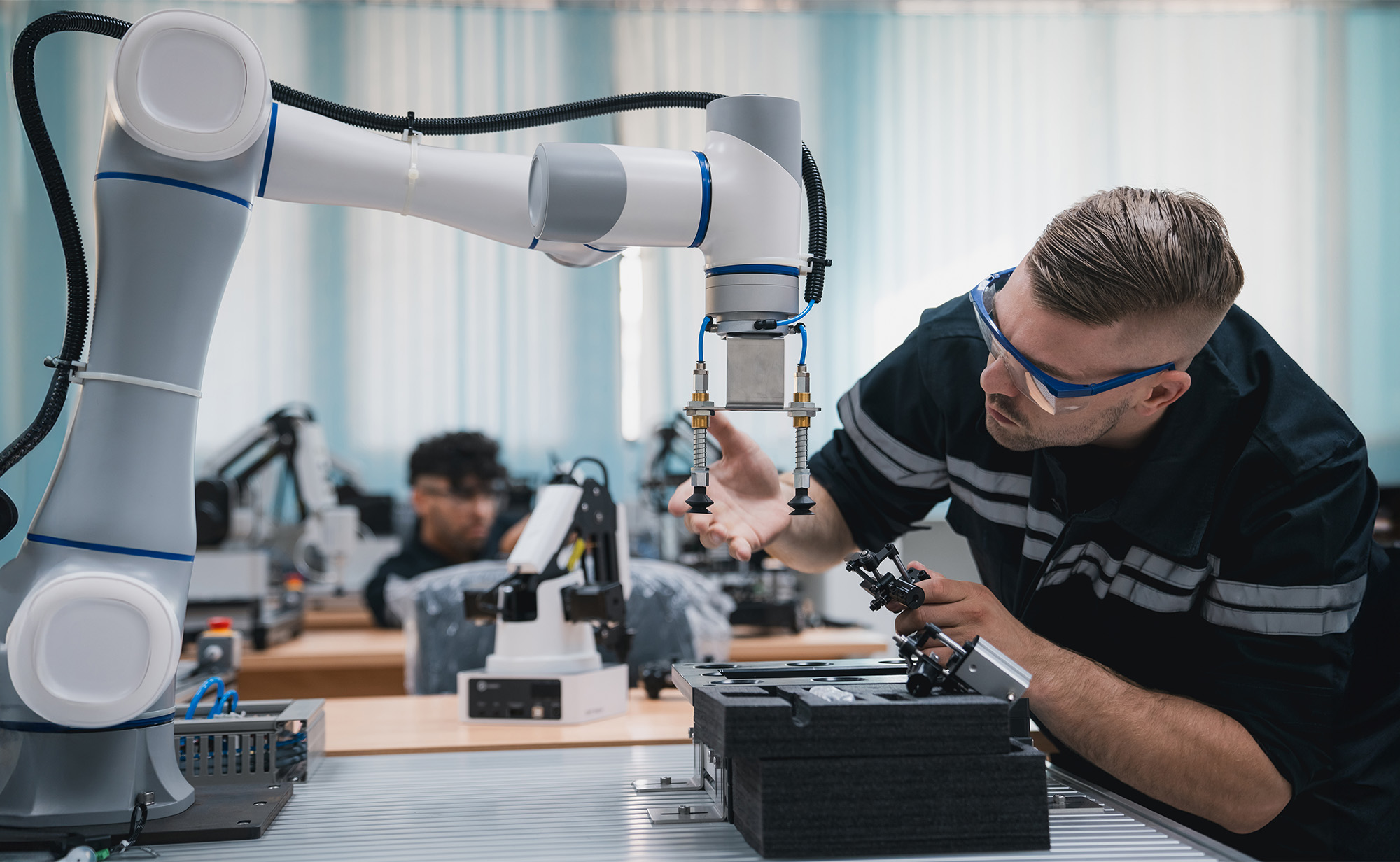 Student engineer Assembling Robotic Arm with computer in Technology Workshop. Service Engineer Holding Robot Controller and Checking Robotic Arm Welding Hardware.