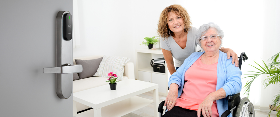 Senior woman with a nurse. The door is open to her room, displaying the SALTO smart lock