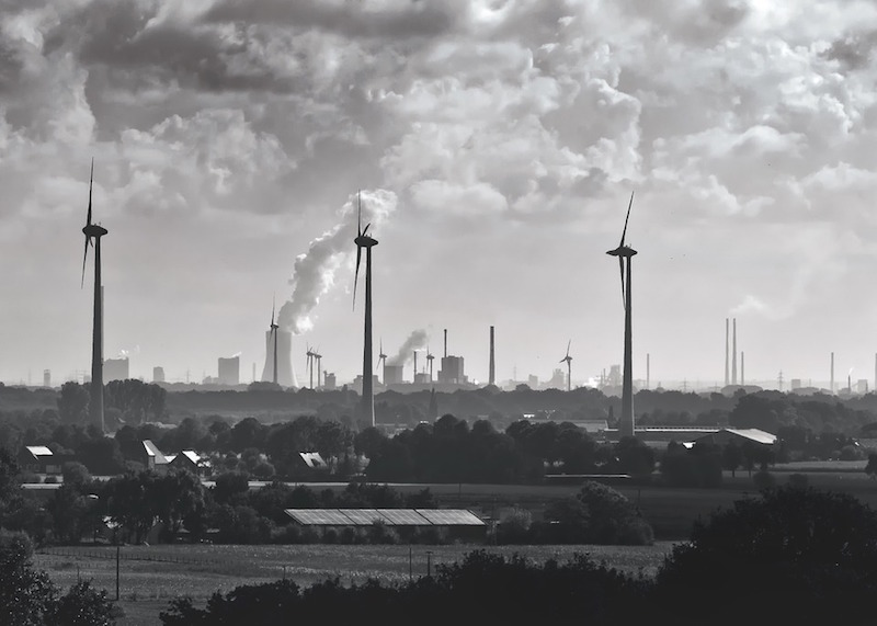 Smokestacks and wind turbines in a rural area