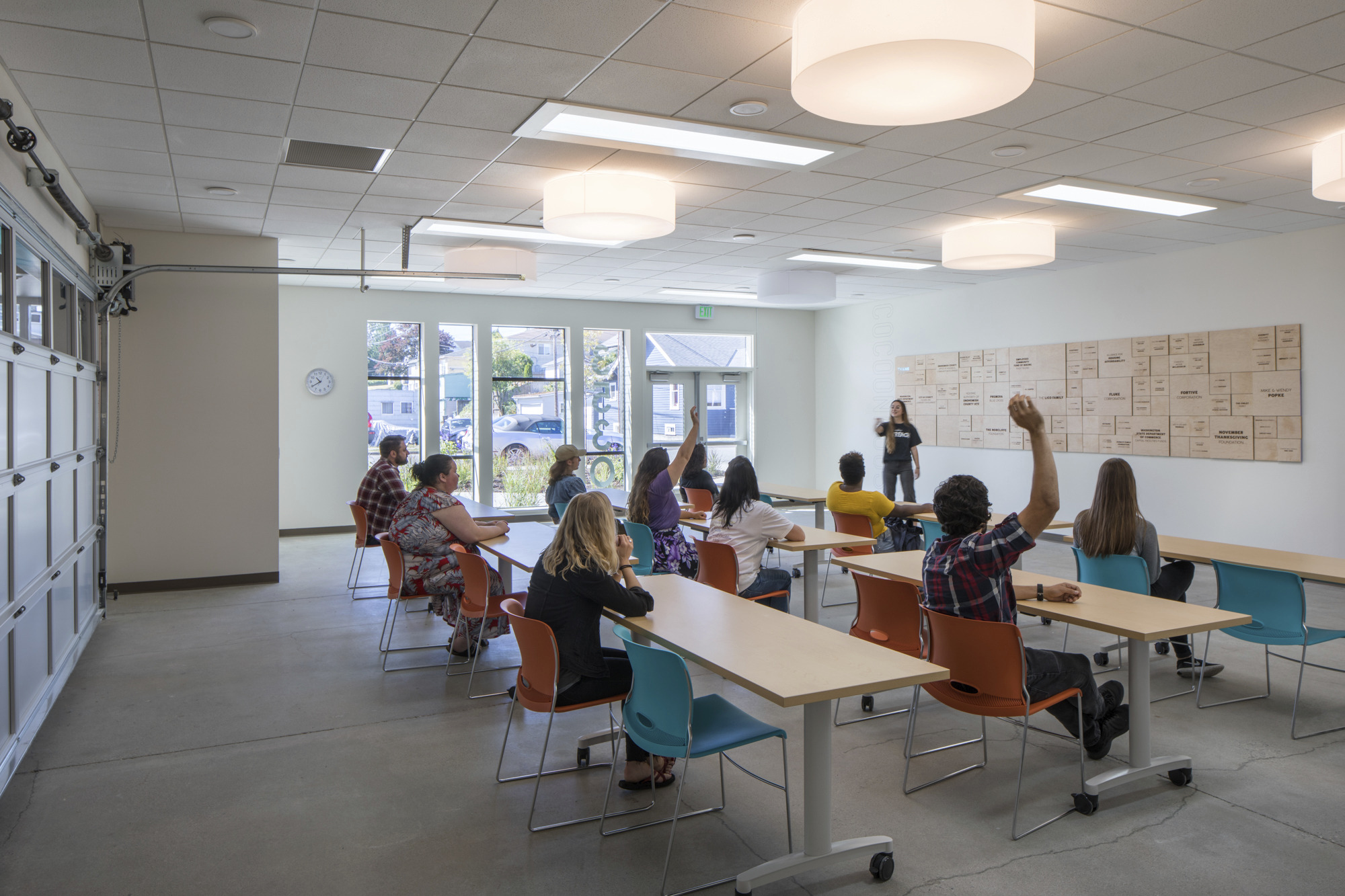 People in classroom setting raising hands