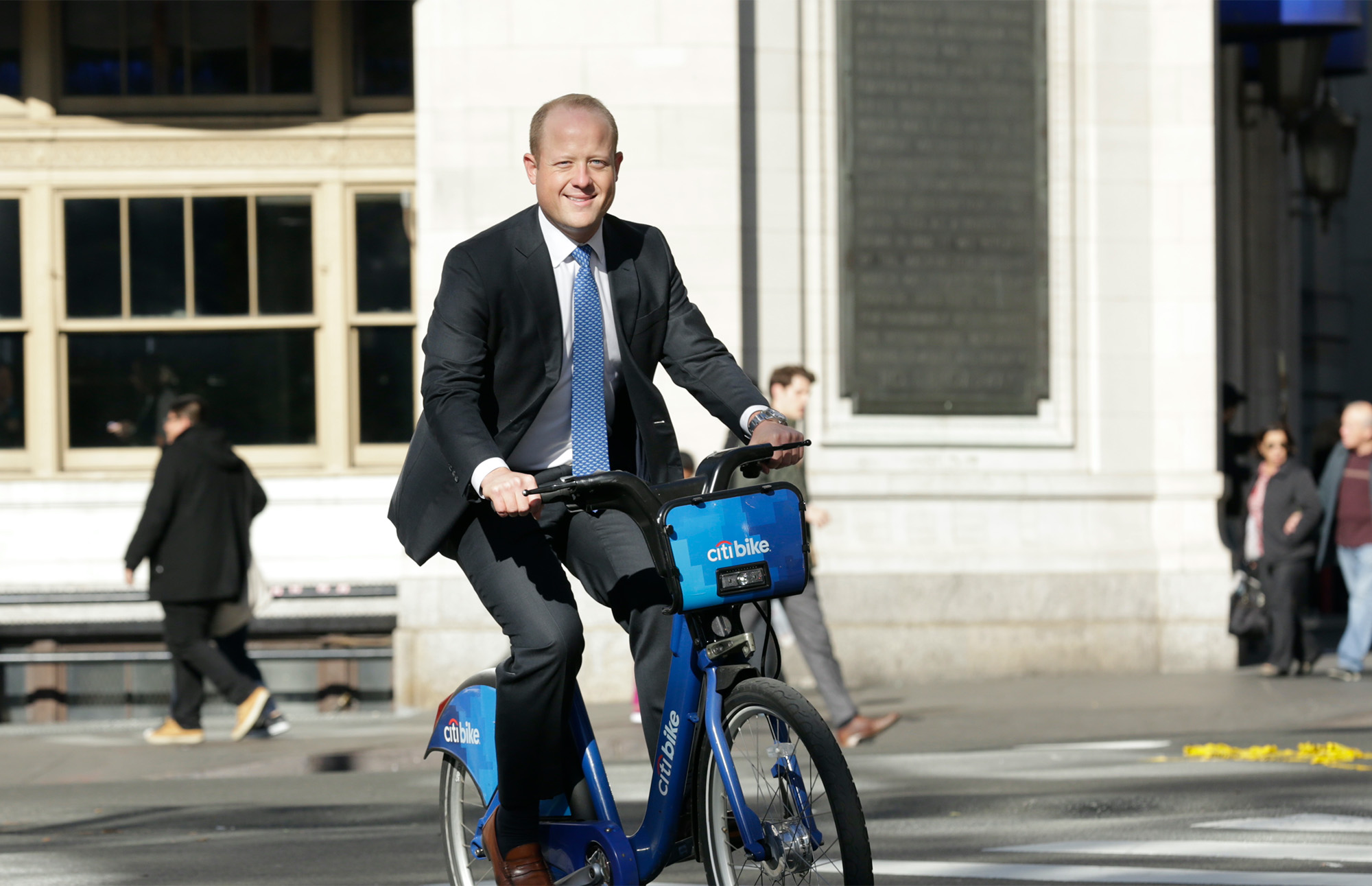 Jason Dubowski riding bike in suit