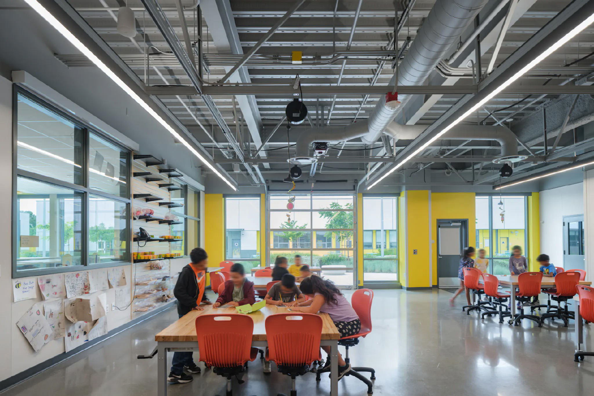 A garage door links an elementary school classroom to the outdoor quad.