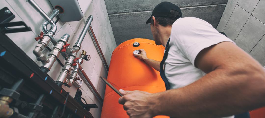 Technician checking the heating system in the boiler room with tablet in hand