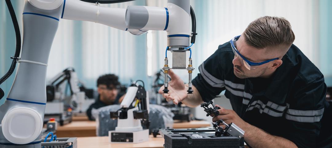 Student engineer Assembling Robotic Arm with computer in Technology Workshop. Service Engineer Holding Robot Controller and Checking Robotic Arm Welding Hardware.