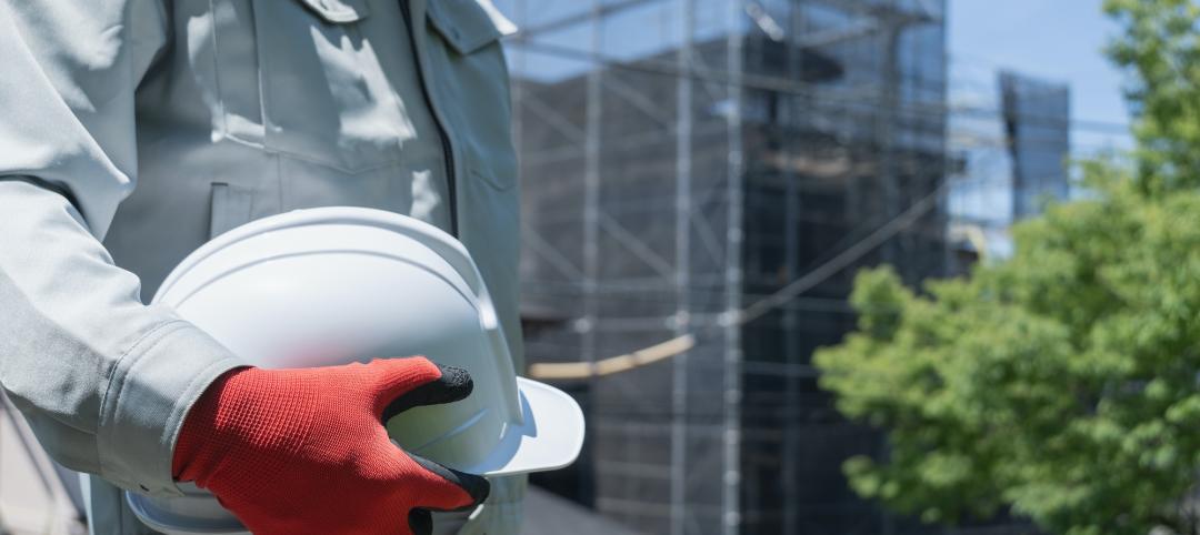 Construction worker holding hard hat at job site